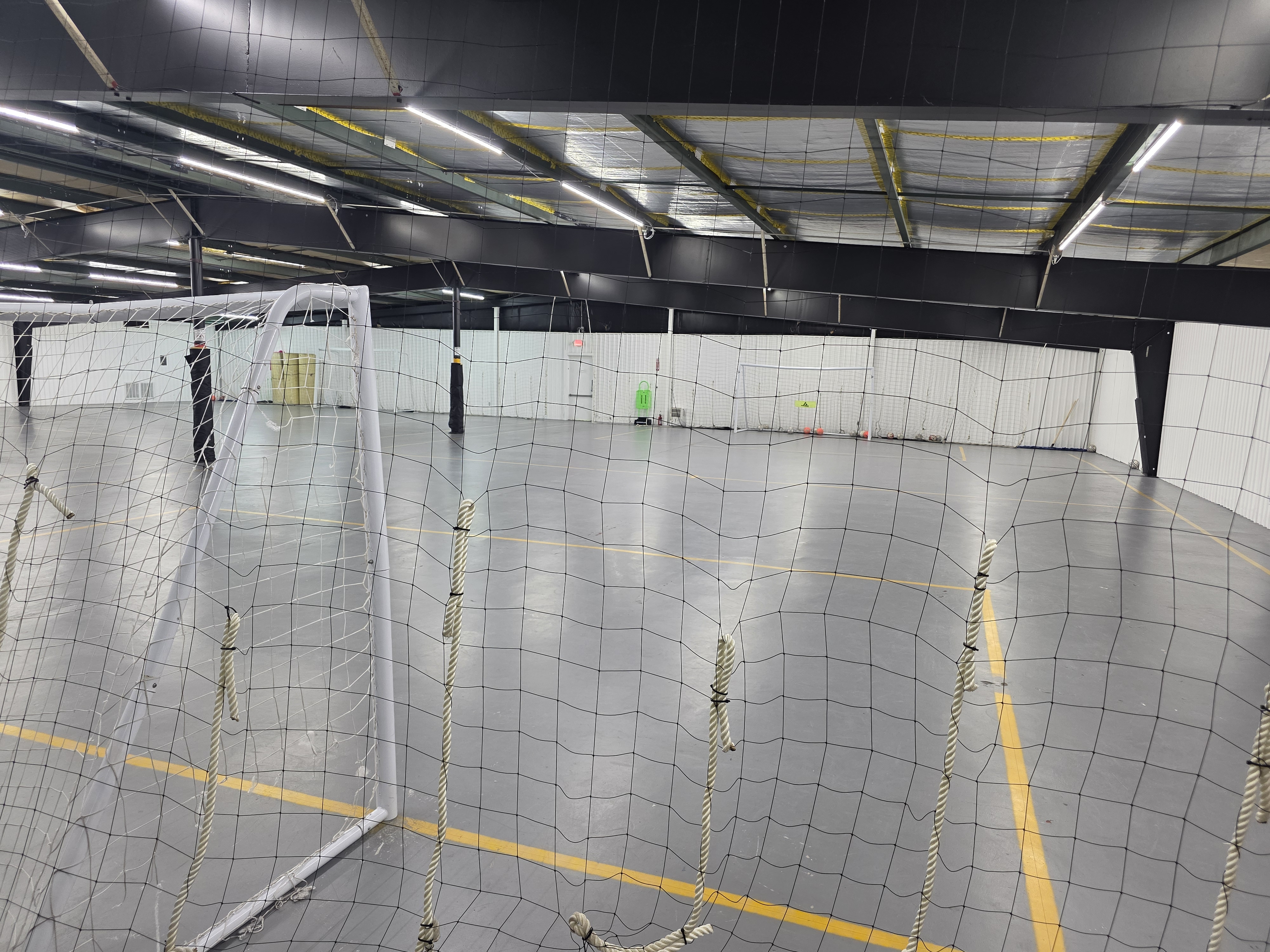 View through a futsal goal and net across the Jacksonville Futsal Academy indoor court